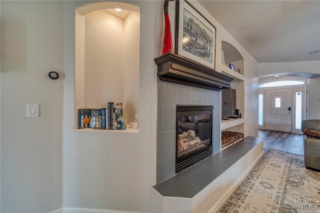 living room featuring arched walkways, a fireplace, wood finished floors, and visible vents