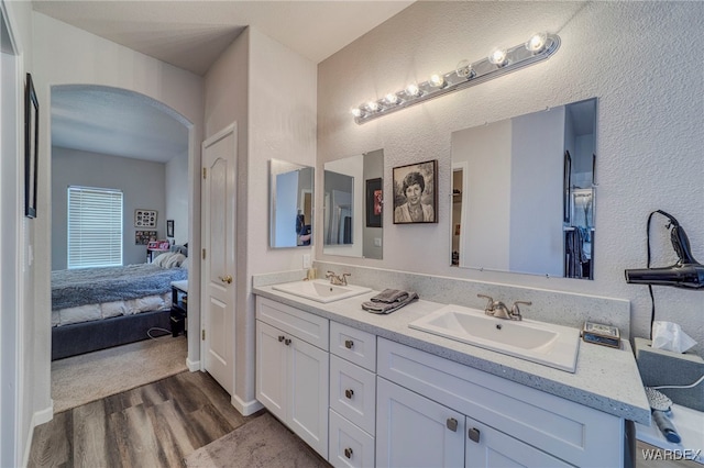 ensuite bathroom with wood finished floors, double vanity, a sink, and ensuite bathroom