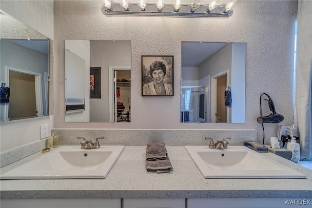 bathroom featuring double vanity, a sink, and a textured wall