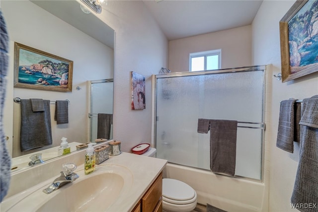 full bathroom featuring enclosed tub / shower combo, vanity, and toilet