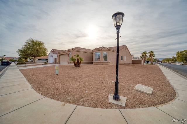 view of front of property with a tile roof, driveway, an attached garage, and stucco siding