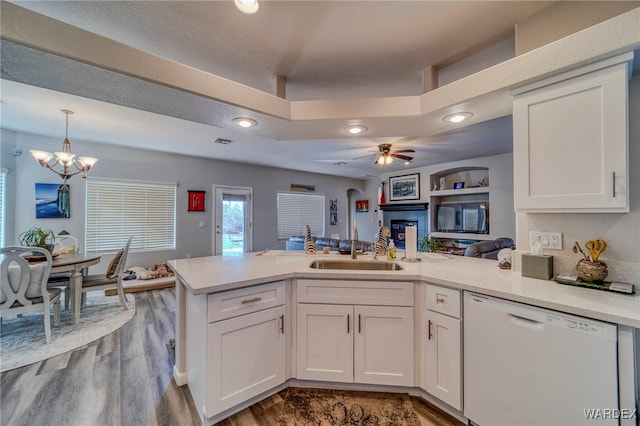 kitchen with white dishwasher, a peninsula, a sink, white cabinets, and open floor plan