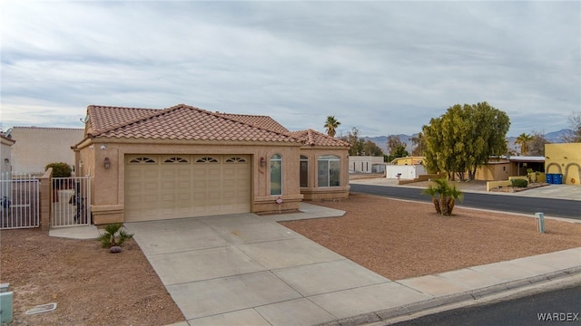 mediterranean / spanish home featuring a mountain view, a garage, a tile roof, concrete driveway, and stucco siding