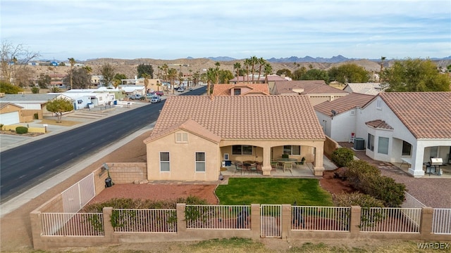 rear view of property featuring a patio, a fenced front yard, a residential view, a tiled roof, and stucco siding