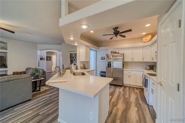 kitchen featuring stainless steel fridge, arched walkways, white cabinets, white range with electric cooktop, and a sink