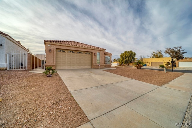 mediterranean / spanish home featuring a tile roof, driveway, fence, and stucco siding