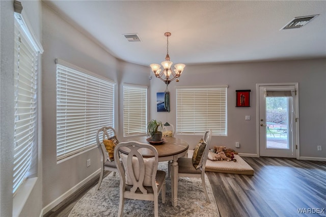 dining space with a chandelier, dark wood-style flooring, visible vents, and baseboards