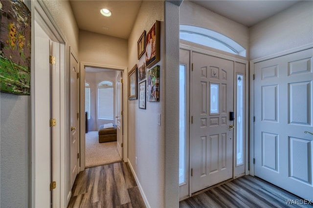 entryway featuring dark wood-style floors, a textured wall, baseboards, and recessed lighting