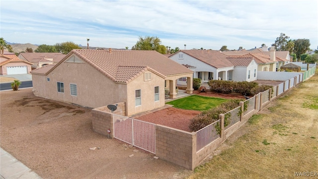 view of front facade featuring fence private yard, a tiled roof, a residential view, and stucco siding