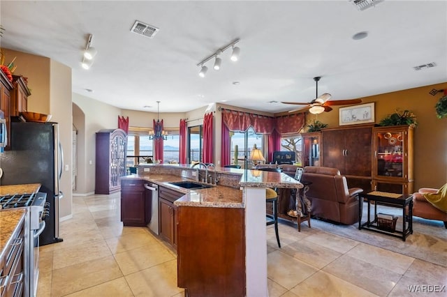 kitchen with arched walkways, stainless steel appliances, a sink, visible vents, and open floor plan