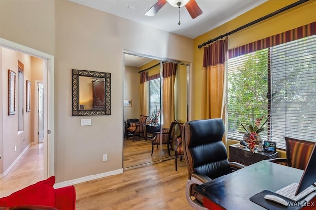 office space with light wood finished floors, baseboards, and a ceiling fan