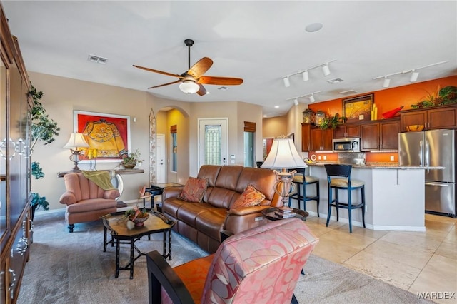 living area with visible vents, arched walkways, a ceiling fan, rail lighting, and light tile patterned flooring