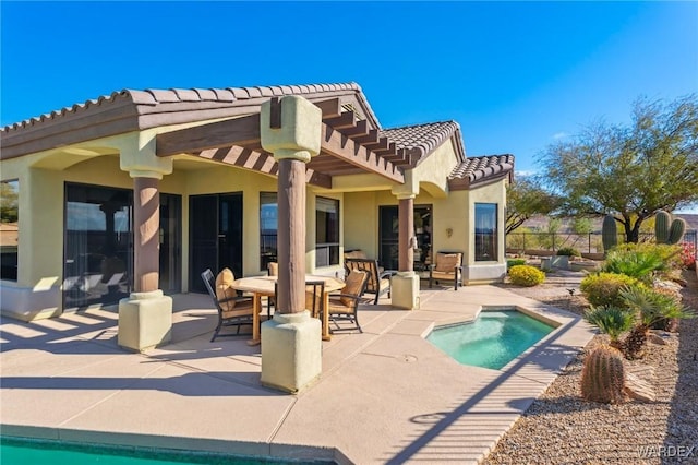 back of house with an outdoor pool, a tiled roof, fence, a patio area, and stucco siding