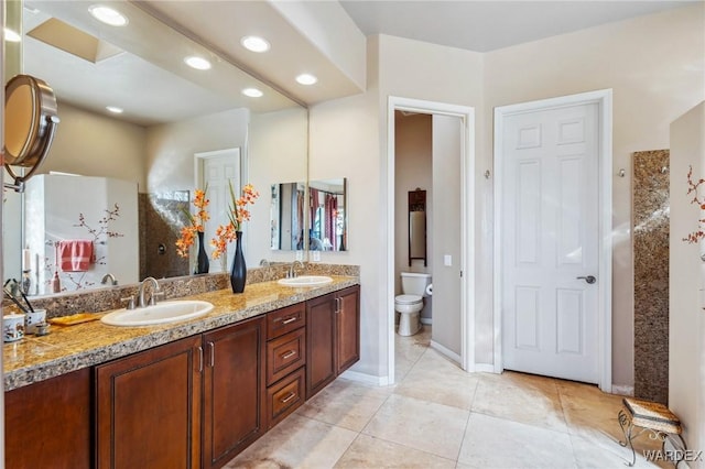 bathroom with double vanity, tile patterned flooring, a sink, and toilet