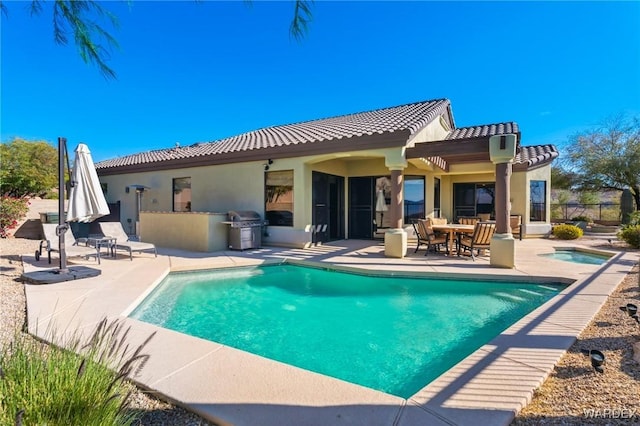 back of property featuring a patio area, an outdoor pool, and exterior kitchen