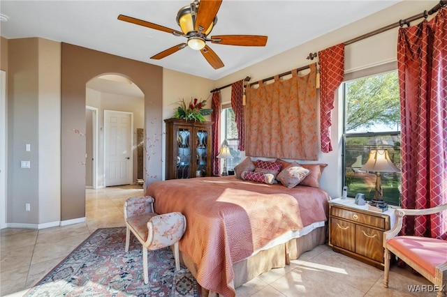 bedroom with arched walkways, ceiling fan, and baseboards