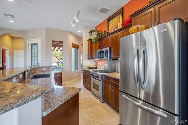 kitchen featuring arched walkways, light tile patterned flooring, a sink, visible vents, and appliances with stainless steel finishes