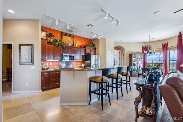 kitchen featuring a breakfast bar area, stainless steel appliances, open floor plan, hanging light fixtures, and an island with sink