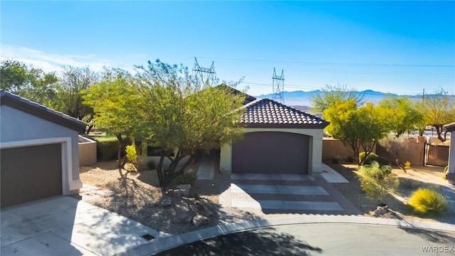 view of front of house with stucco siding, a mountain view, fence, a garage, and a tiled roof