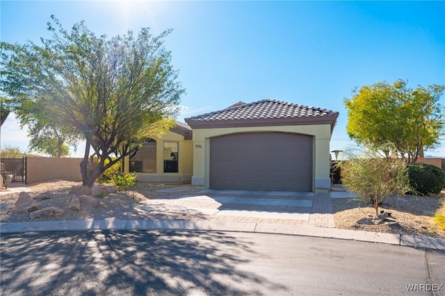 mediterranean / spanish-style home featuring stucco siding, concrete driveway, fence, a garage, and a tiled roof