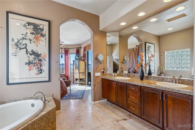 full bathroom featuring double vanity, a tub to relax in, tile patterned flooring, and a sink