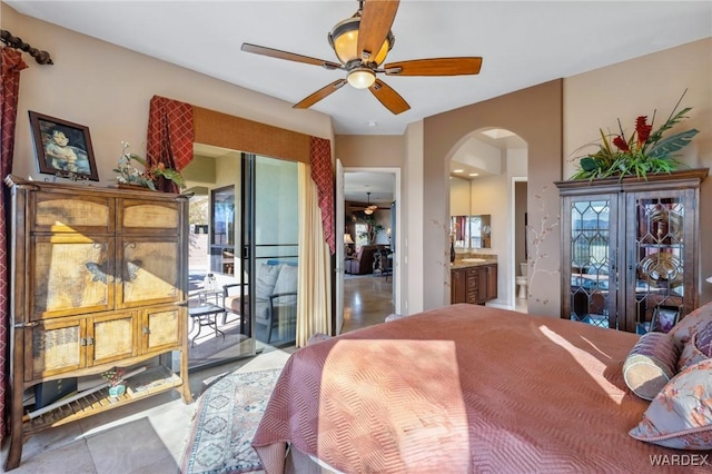 bedroom featuring arched walkways, ensuite bathroom, a ceiling fan, and access to exterior