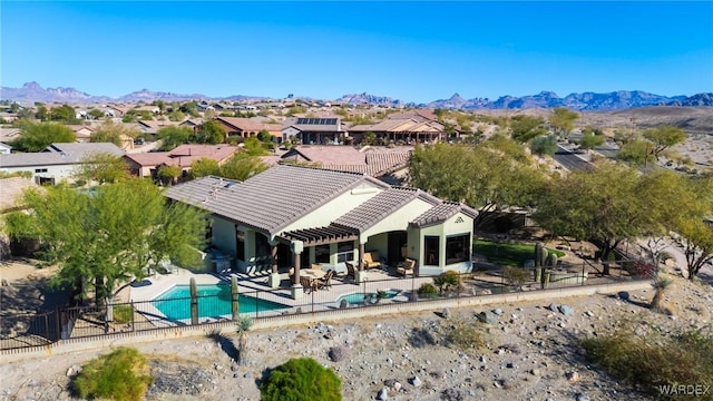 back of house featuring a residential view, a tiled roof, fence, a patio area, and a mountain view