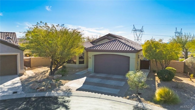 view of front of house with stucco siding, an attached garage, fence, driveway, and a tiled roof