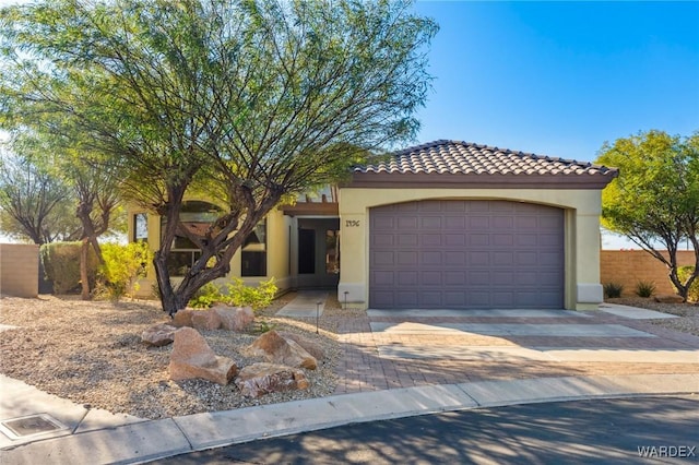 mediterranean / spanish home featuring a garage, a tiled roof, decorative driveway, and stucco siding