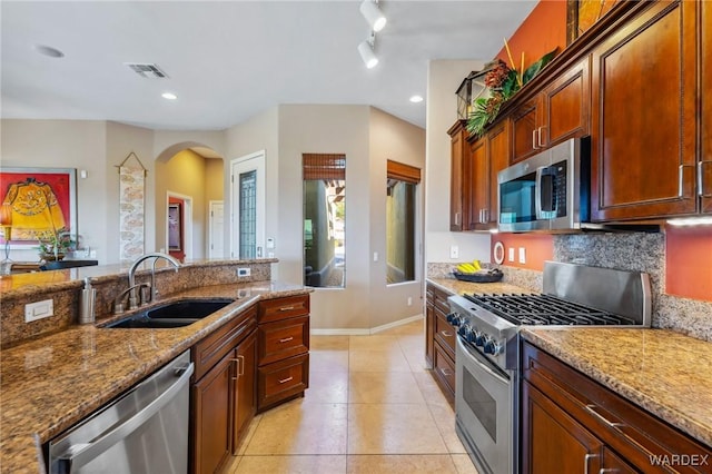 kitchen featuring light tile patterned floors, light stone counters, stainless steel appliances, a sink, and visible vents