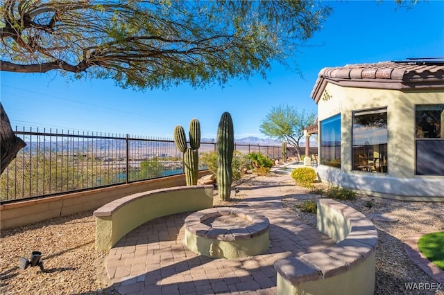 view of patio with an outdoor fire pit and fence