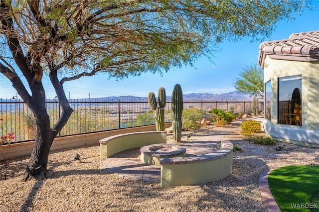 view of yard featuring a fenced backyard, a fire pit, and a mountain view