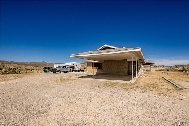 view of property exterior featuring driveway, brick siding, and an attached carport