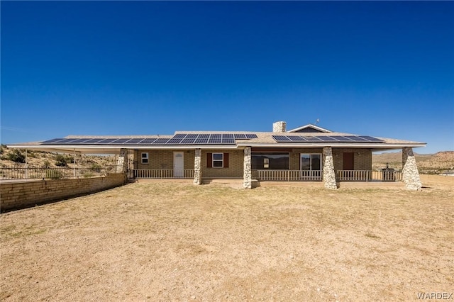 view of front of property with solar panels, brick siding, and a chimney