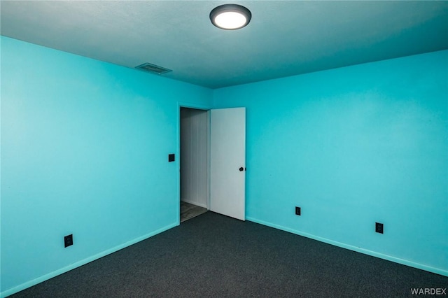 spare room featuring baseboards, visible vents, and dark colored carpet