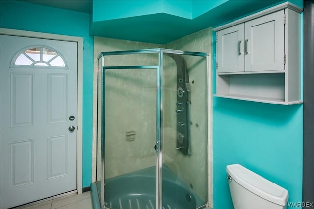 bathroom with tile patterned flooring, a shower with shower door, and toilet