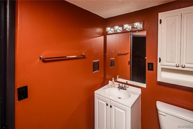 bathroom featuring a textured ceiling, vanity, and toilet