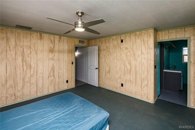 unfurnished bedroom with visible vents, wood walls, finished concrete flooring, and ceiling fan