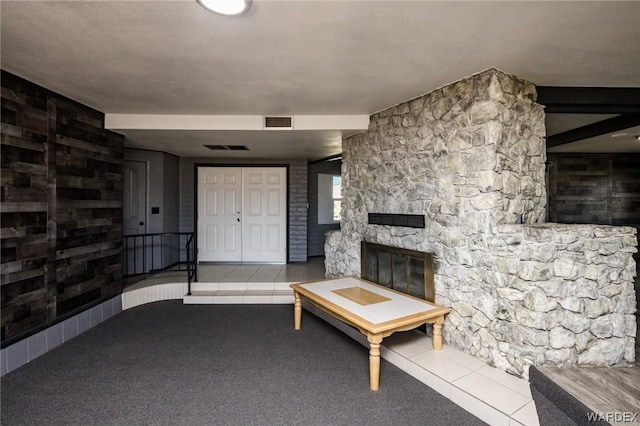 unfurnished living room with light carpet, light tile patterned floors, visible vents, and a stone fireplace