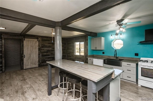 kitchen featuring a barn door, white appliances, a sink, white cabinets, and light wood finished floors