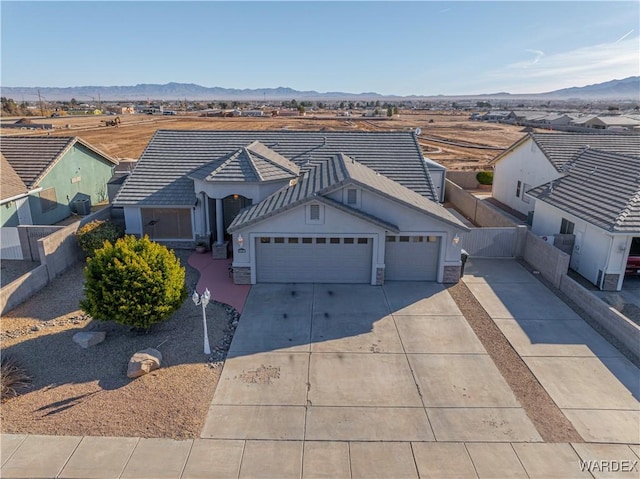 view of front facade featuring driveway, a tile roof, fence, and a mountain view