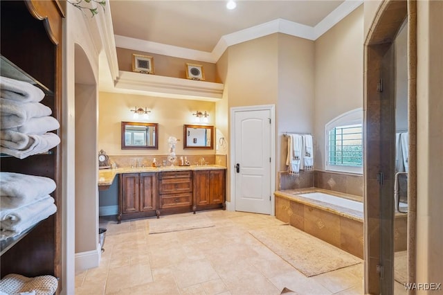 bathroom with double vanity, a stall shower, ornamental molding, a garden tub, and a sink