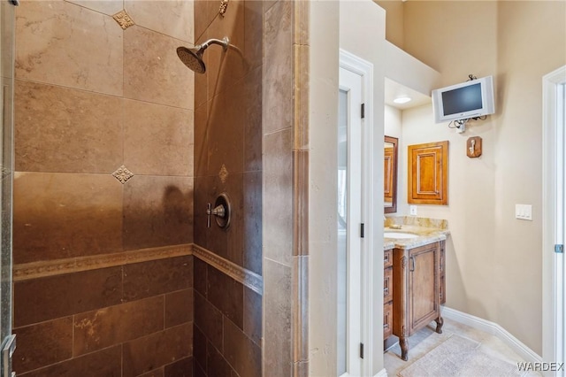 full bath featuring baseboards, tiled shower, and vanity