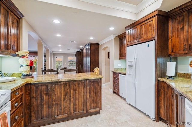 kitchen with arched walkways, a peninsula, white appliances, and light stone countertops