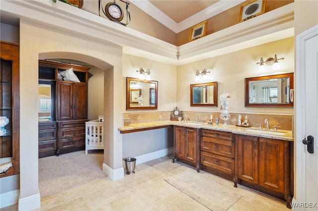 bathroom featuring double vanity, ornamental molding, a sink, and baseboards