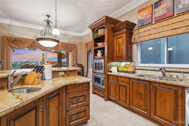 kitchen with hanging light fixtures, ornamental molding, light stone counters, and a sink