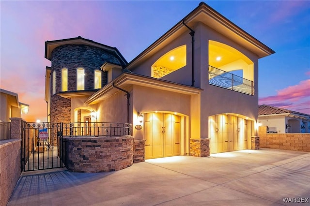 view of front of property featuring an attached garage, stone siding, a gate, and stucco siding