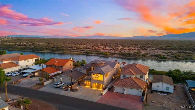 aerial view at dusk featuring a residential view and a water view