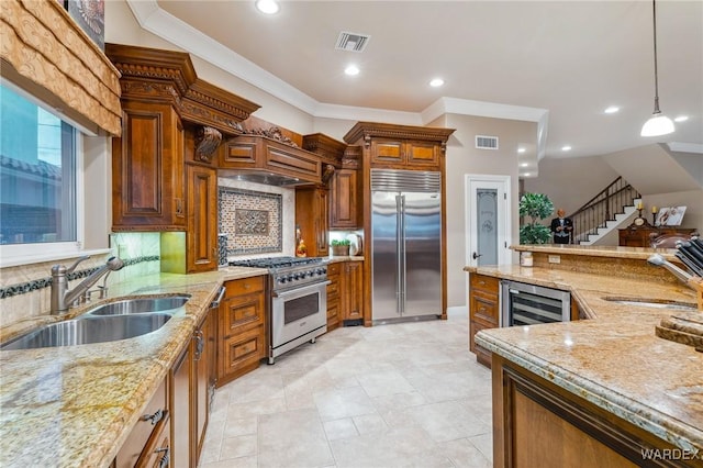 kitchen featuring visible vents, wine cooler, high quality appliances, decorative light fixtures, and a sink