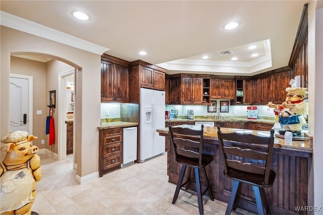 kitchen featuring arched walkways, white appliances, ornamental molding, and visible vents